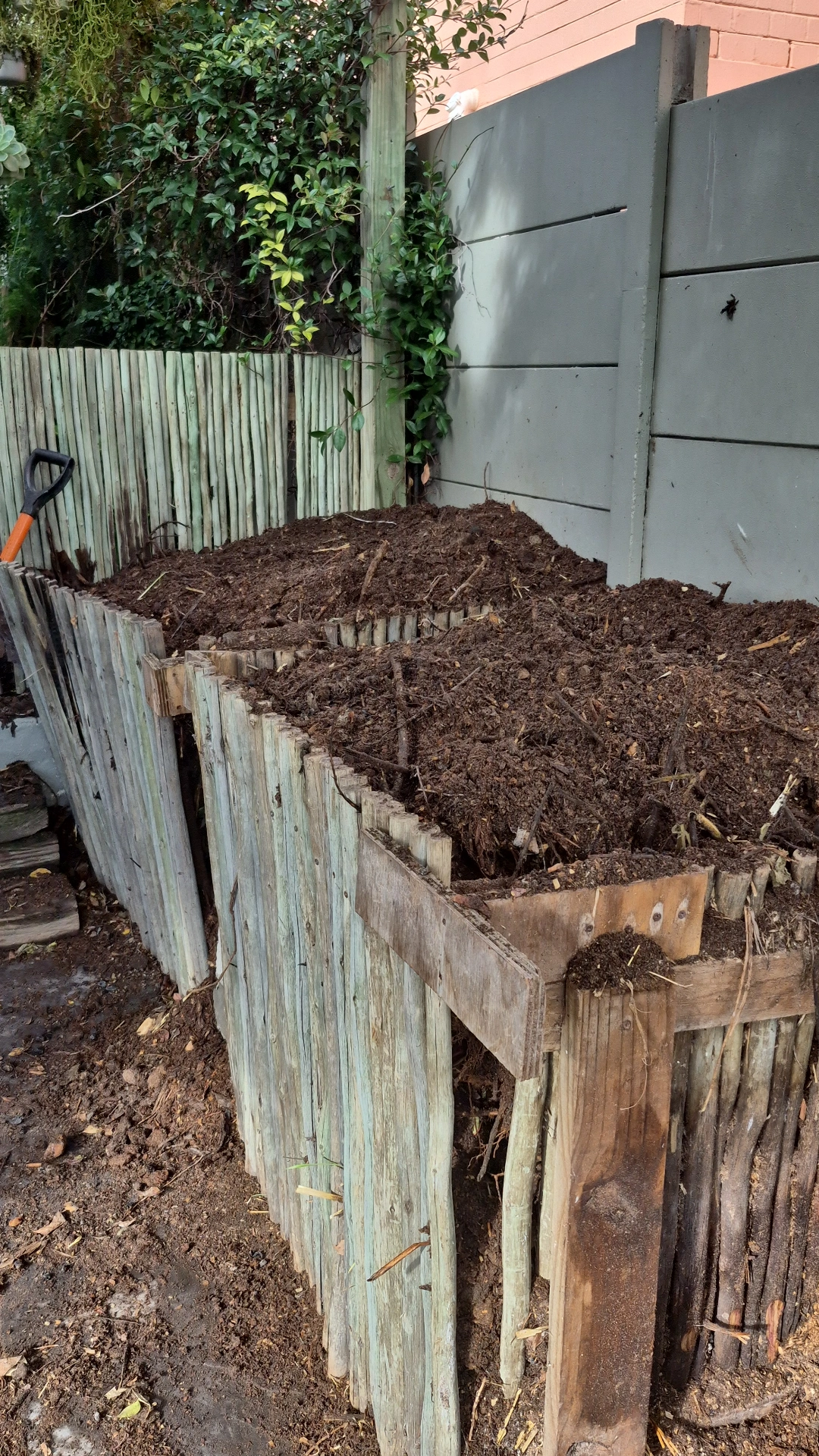 Twin wooden slat compost bins in a Cape Town backyard, filled with maturing compost