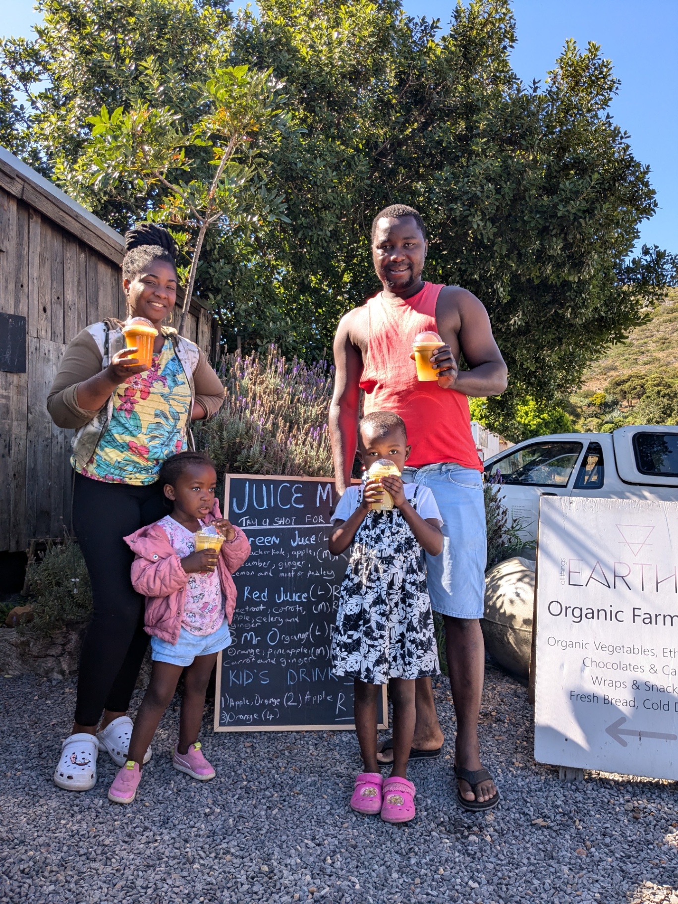 Family posing with fresh juices by the juice menu chalkboard